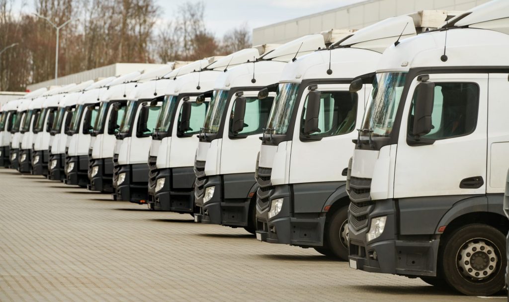 Flotta di camion allineati in un'area logistica, pronti per le novità sulla mobilità sostenibile che saranno presentate a LetExpo 2025